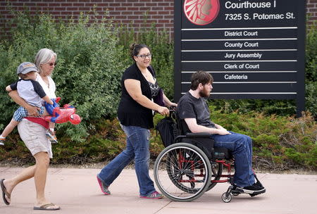 Aurora theater shooting victim Caleb Medley (in wheelchair) arrives with his wife Katie (pushing him) and son Hugo carried by an unidentified woman at Arapahoe County Courthouse in Centennial, Colorado July 16, 2015, to hear the verdict in the trial. REUTERS/Rick Wilking