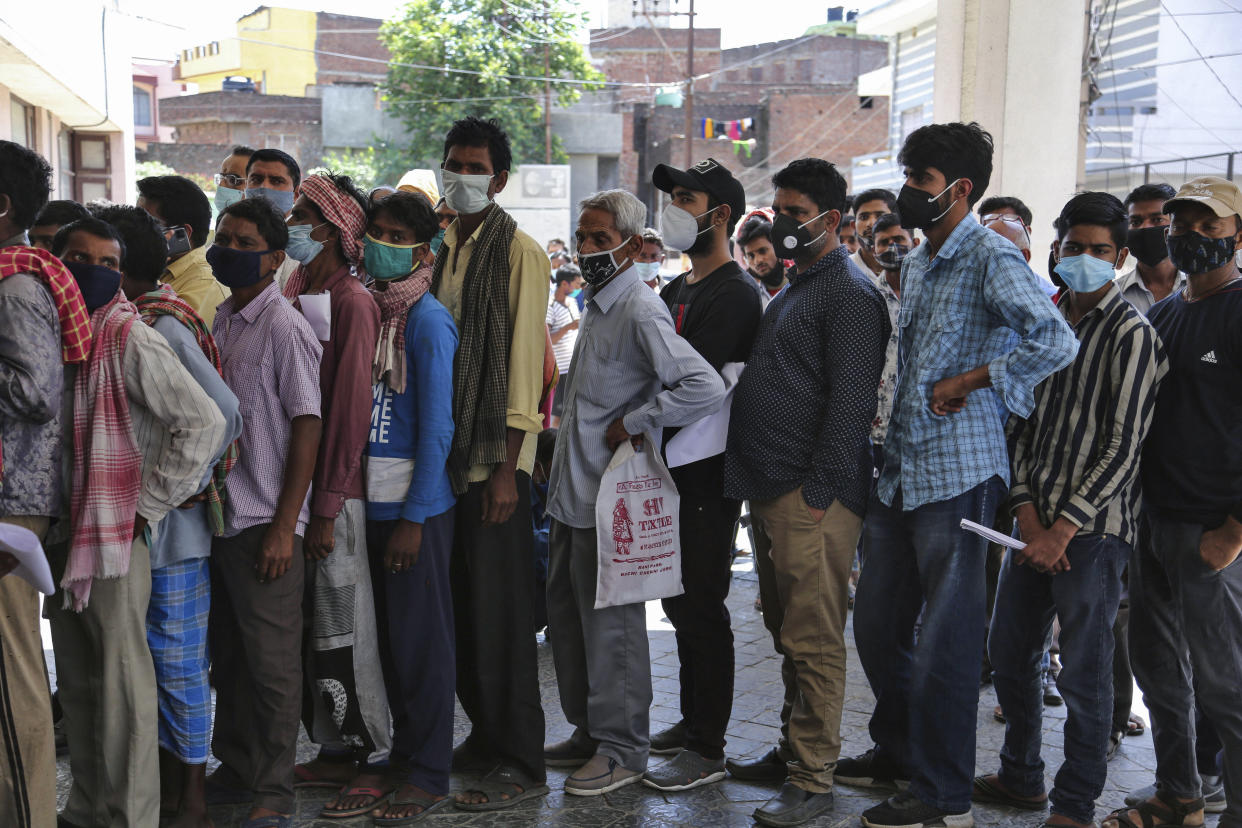 People wearing face masks as a precaution against the coronavirus line up without any physical distancing to get tested for COVID-19 at a government hospital in Jammu, India, Monday, April 19, 2021. India now has reported more than 15 million coronavirus infections, a total second only to the United States. (AP Photo/Channi Anand)