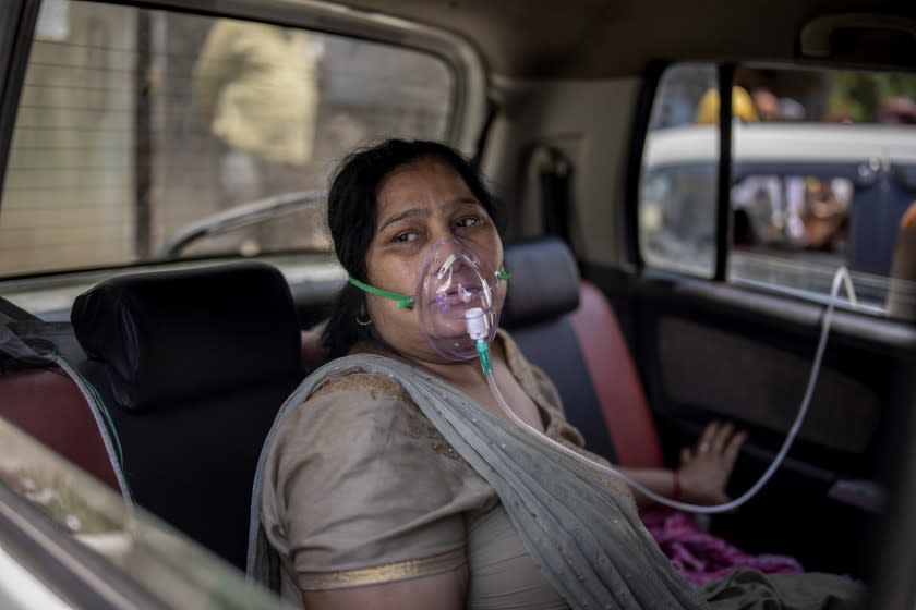 A COVID-19 patient sits inside a car and breathes with the help of oxygen provided by a Gurdwara, a Sikh house of worship, in New Delhi, India, Saturday, April 24, 2021. India's medical oxygen shortage has become so dire that this gurdwara began offering free breathing sessions with shared tanks to COVID-19 patients waiting for a hospital bed. They arrive in their cars, on foot or in three-wheeled taxis, desperate for a mask and tube attached to the precious oxygen tanks outside the gurdwara in a neighborhood outside New Delhi. (AP Photo/Altaf Qadri)
