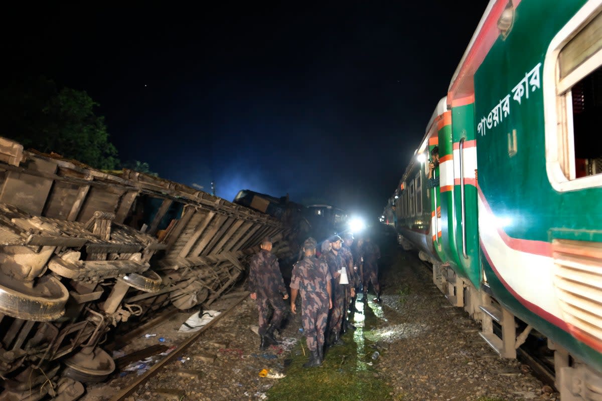 Policemen stand guard at the site of an accident where a cargo train hit a passenger train at Bhairab, Kishoreganj district, Bangladesh, Monday, 23 October 2023, leaving more than dozen people dead and scores injured (Associated Press)