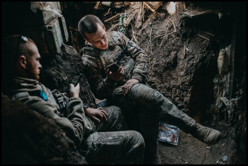 A navigator, with the call sign Actor, and the drone operator Sapsan rest while looking at their phones in a forward bunker position on the southern front line near Robotyne Sept. 14. (Photo for The Washington Post by Wojciech Grzedzinski)