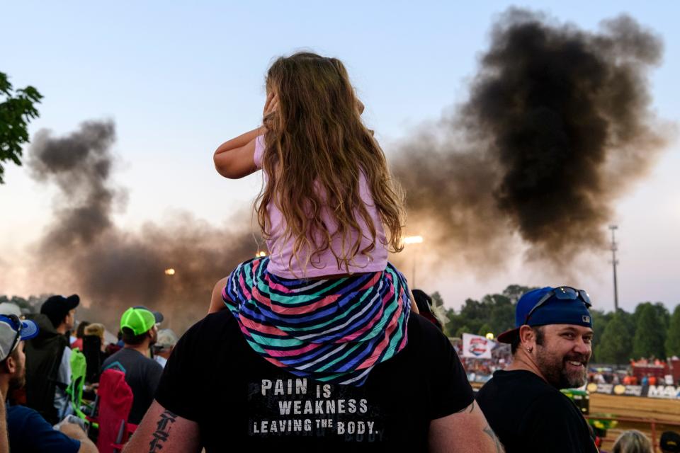 Adelyn Keller, 4, covers her ears as she sits on her father Trevor Keller's shoulders for a better view of the International Harvester tractor rolling by during the Lucas Oil Pro Pulling League Professional Tractor Pull event at the Vanderburgh County Fair grandstand, Friday evening, July 27, 2018. 