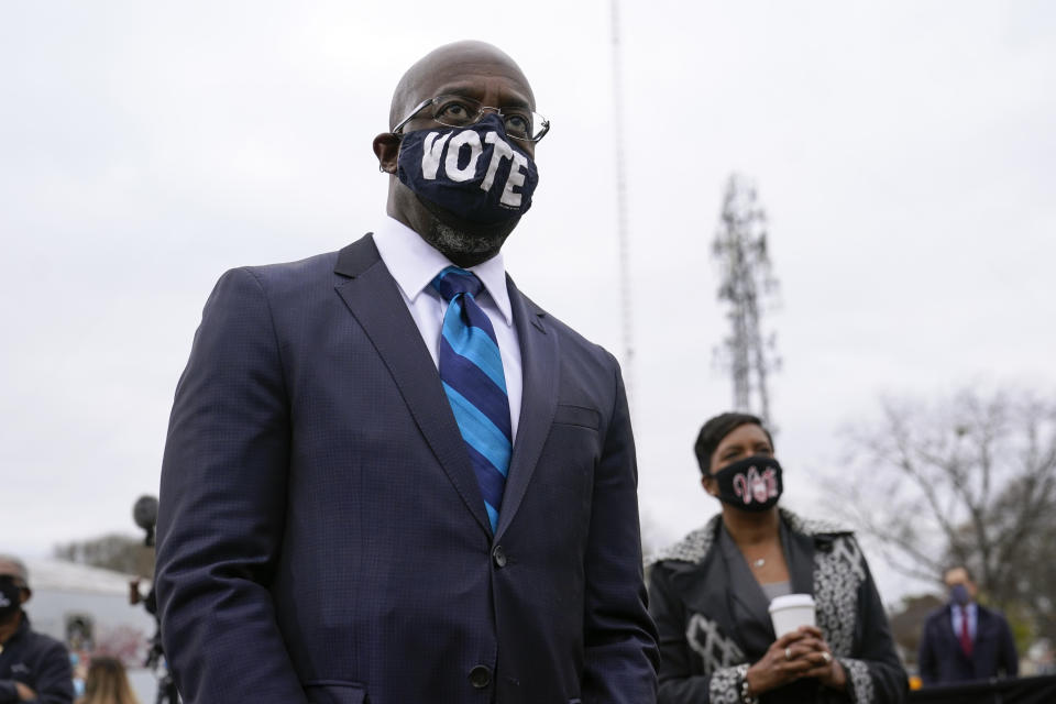 Georgia Democratic candidate for U.S. Senate Raphael Warnock listens as President-elect Joe Biden speaks at a drive-in rally for Warnock and Jon Ossoff, Tuesday, Dec. 15, 2020, in Atlanta. (AP Photo/Patrick Semansky)