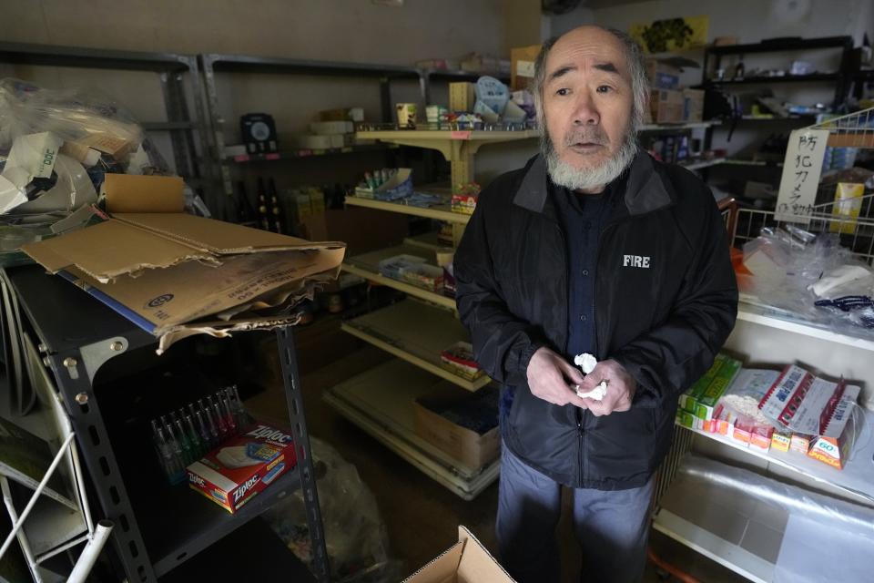A shop owner stands at his shop in Wajima in the Noto peninsula facing the Sea of Japan, northwest of Tokyo, Sunday, Jan. 7, 2024. Monday's temblor decimated houses, twisted and scarred roads and scattered boats like toys in the waters, and prompted tsunami warnings. (AP Photo/Hiro Komae)