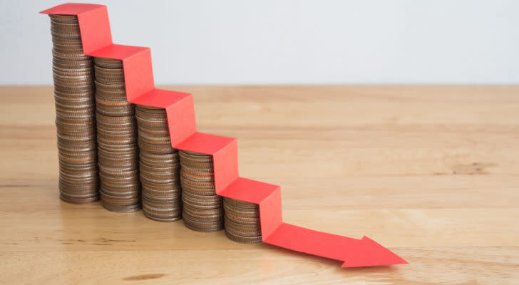 Photo of stair of coins with red arrow headed downward over top of the coin stacks