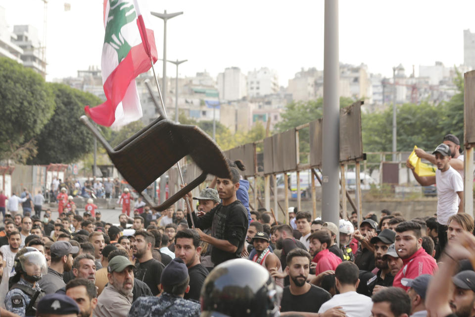 Hezbollah supporters throw a chair on anti-government protesters as clash during a protest in Beirut, Lebanon, Friday, Oct. 25, 2019. Leader of Lebanon's Hezbollah calls on his supporters to leave the protests to avoid friction and seek dialogue instead. (AP Photo/Hassan Ammar)