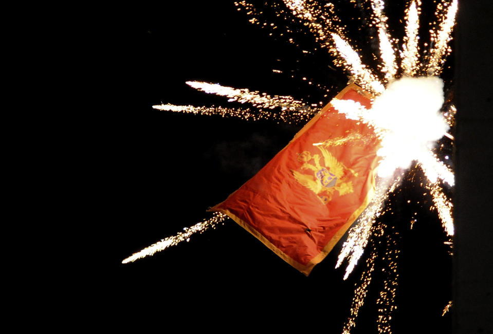 The Montenegrin flag flying from the Montenegrin Embassy, is targeted with fireworks by Serbian ultra-nationalists during a protest against a religion rights law adopted by Montenegro's parliament last month, during a mass protest in Belgrade, Serbia, Thursday, Jan. 2, 2020. Montenegro on Friday strongly denounced aggression against its embassy in Serbia during a protest by some thousands of ultra-nationalists, saying the action represented an attack on the country's independence. (AP Photo/Ana Paunkovic)