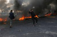 Protesters play football next to burning tires during ongoing anti-government protests in Basra