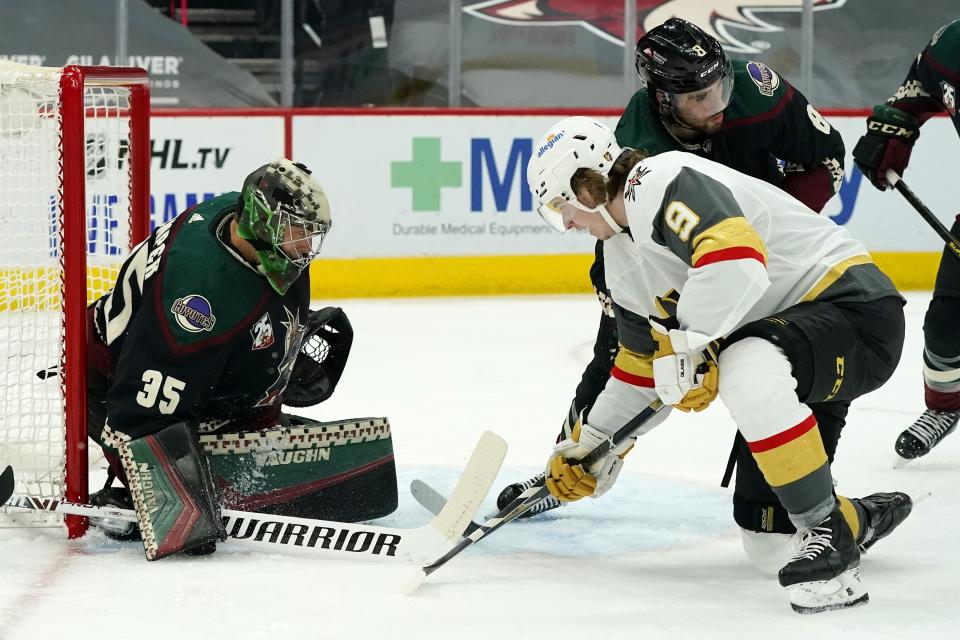 Arizona Coyotes goaltender Darcy Kuemper (35) makes a save on a shot by Vegas Golden Knights center Cody Glass (9) as Coyotes center Nick Schmaltz (8) defends during the second period of an NHL hockey game Friday, Jan. 22, 2021, in Glendale, Ariz. (AP Photo/Ross D. Franklin)