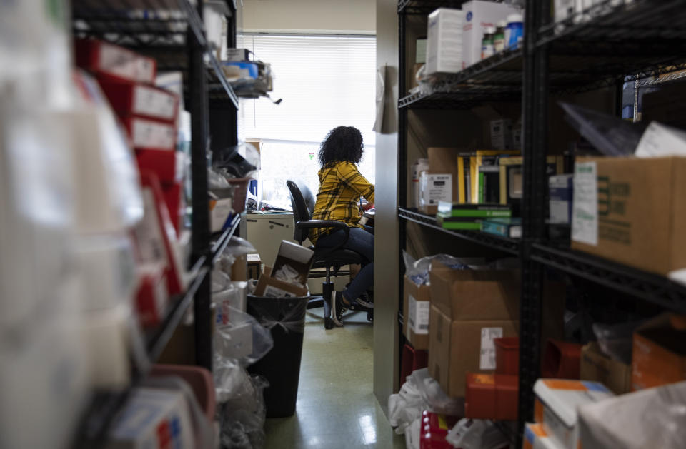 In this March 6, 2020, photo, a supply room is stocked as an employee works in the background at the South Shore Rehabilitation and Skilled Care Center, in Rockland, Mass. From Miami to Seattle, nursing homes and other facilities for the elderly are stockpiling masks and thermometers, preparing for staff shortages and screening visitors to protect a particularly vulnerable population from the deadly new coronavirus. (AP Photo/David Goldman)