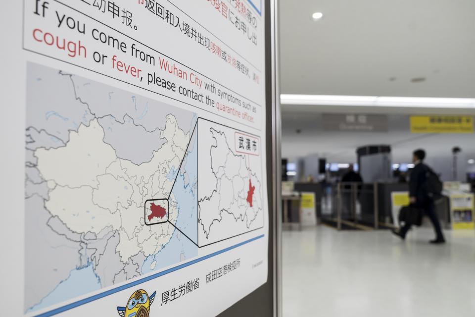 A passenger walks past a notice for travelers from Wuhan, China, displayed near a quarantine station at Narita airport on Jan. 17 in Japan.