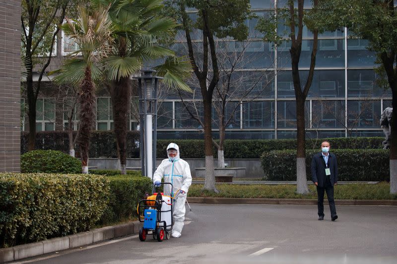 A worker in PPE disinfects the pavement after members of the World Health Organization (WHO) team arrived at the Hubei Animal Epidemic Disease Prevention and Control Center in Wuhan