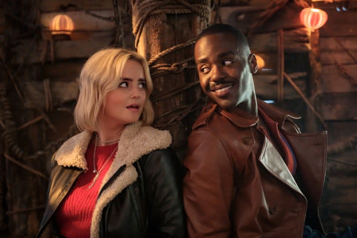 Ruby and the Doctor smile while tied to a post together in Doctor Who.