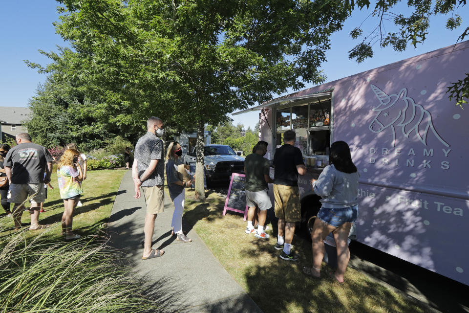 Customers line up to order from the Dreamy Drinks food truck, Monday, Aug. 10, 2020, near the suburb of Lynnwood, Wash., north of Seattle. Long seen as a feature of city living, food trucks are now finding customers in the suburbs during the coronavirus pandemic as people are working and spending most of their time at home. (AP Photo/Ted S. Warren)