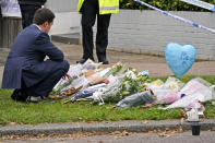 A man leaves flowers on the road leading to the Belfairs Methodist Church in Eastwood Road North, in Leigh-on-Sea, Essex, England, Saturday, Oct. 16, 2021. David Amess, a long-serving member of Parliament was stabbed to death during a meeting with constituents at a church in Leigh-on-Sea on Friday, in what police said was a terrorist incident. A 25-year-old man was arrested in connection with the attack, which united Britain's fractious politicians in shock and sorrow. (AP Photo/Alberto Pezzali)