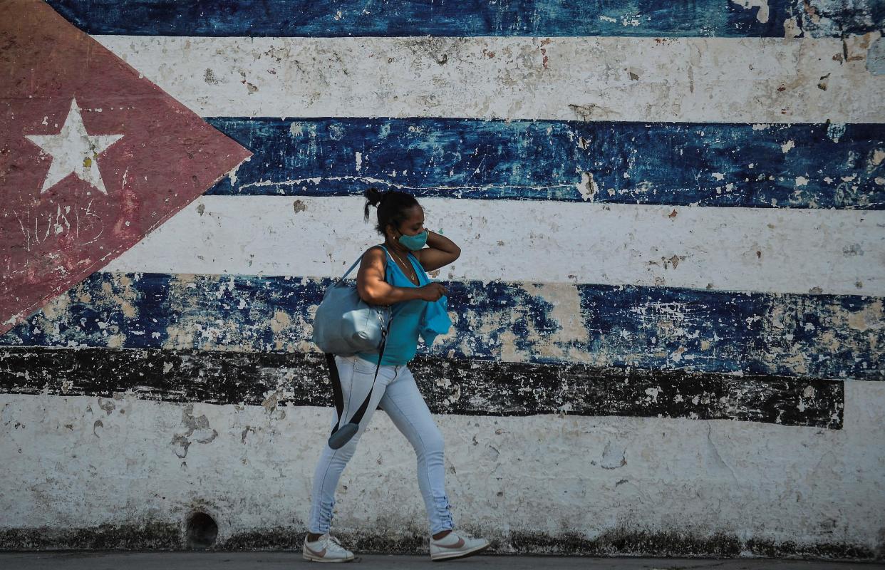 A woman walks near a wall depicting the Cuban flag in Havana as the UN meets in New York (AFP via Getty Images)