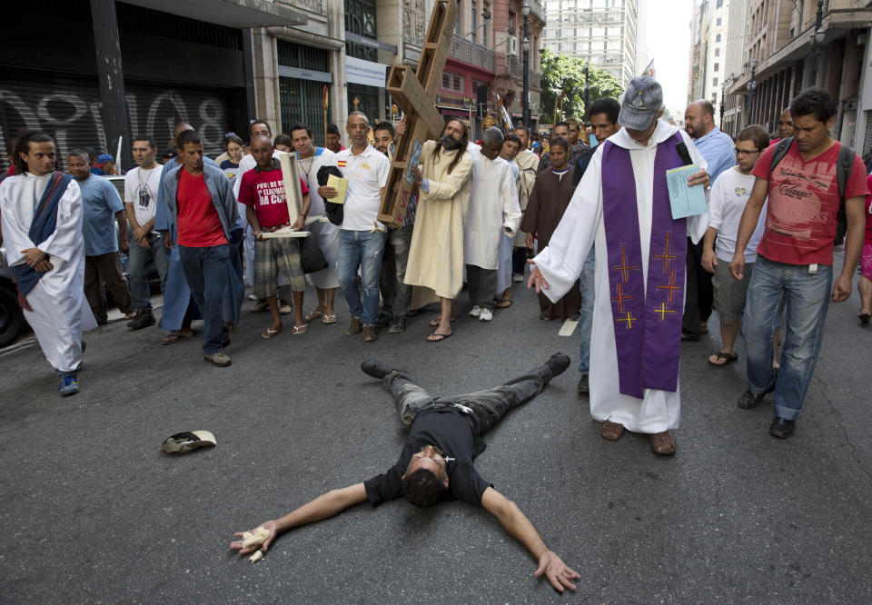 Church volunteers and homeless people participate in a Way of the Cross procession, as a homeless man lies on the ground in downtown Sao Paulo, Brazil, Friday, April 18, 2014. (AP Photo/Andre Penner)
