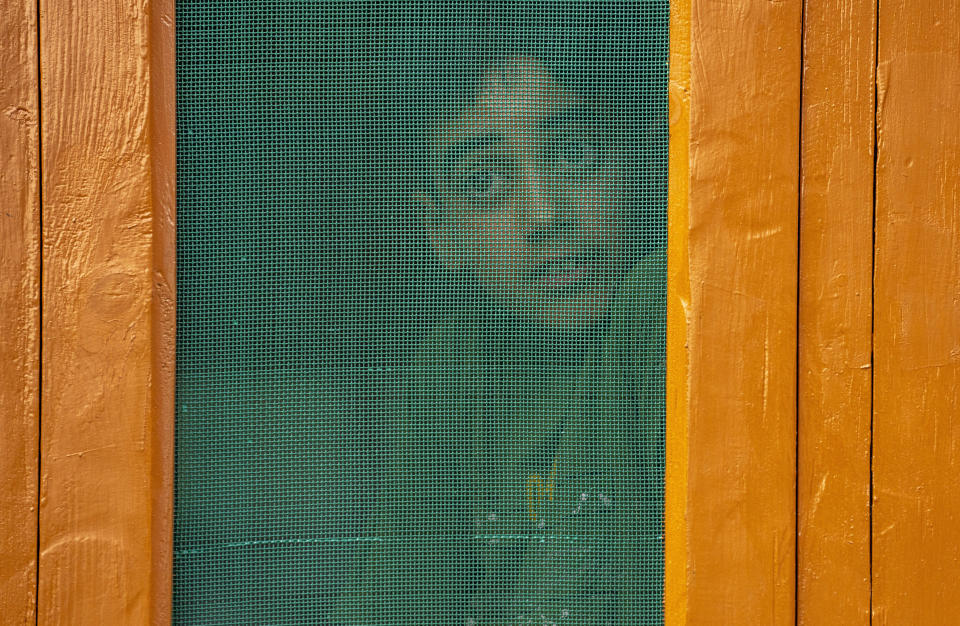 A young boy watches from behind a mesh window as relatives and neighbors of an Indian army solider Waseem Sarvar Bhat, who was killed in a gunbattle with suspected rebels, grieve at his residence in Bandipora, north of Srinagar, Indian controlled Kashmir, Saturday, Aug. 5, 2023. Three Indian soldiers were killed in a gunbattle with rebels fighting against New Delhi's rule in Kashmir, officials said Saturday, as authorities stepped up security on the fourth anniversary since India revoked the disputed region's special status.(AP Photo/Dar Yasin)