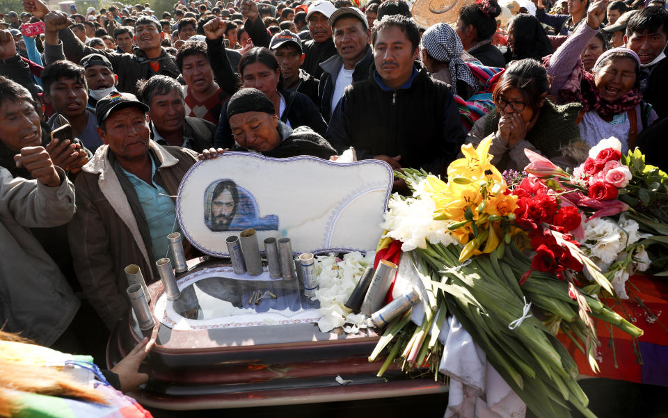 People stand next to the coffin of a supporter of former President Evo Morales killed during clashes with security forces, in Sacaba, Bolivia, Saturday, Nov. 16, 2019. Bolivian security forces clashed with Morales' supporters Friday, leaving at least five people dead, dozens more injured and escalating the challenge to the country's interim government to restore stability. (AP Photo/Juan Karita)