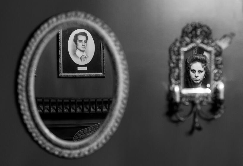 Azusa, CA - October 10: A reflection in a mirror of a portrait hung on the wall, left, and the character Dolores, played by Emma Kuhn, at The Ministry of Peculiarities, one of the most intricate and detailed escape rooms in the Los Angeles area, in Azusa Tuesday, Oct. 10, 2023. The Ministry as a story-room, one where live actors will lead participants through a makeshift haunted house with a disastrous family history. Objects on walls will come alive with theme park trickery, and puzzles are designed primarily to reveal narrative details. Paintings, for instance, adorn a dining hall, but we're made to feel as if the space is haunted by the way the portraits speak to us. (Allen J. Schaben / Los Angeles Times)