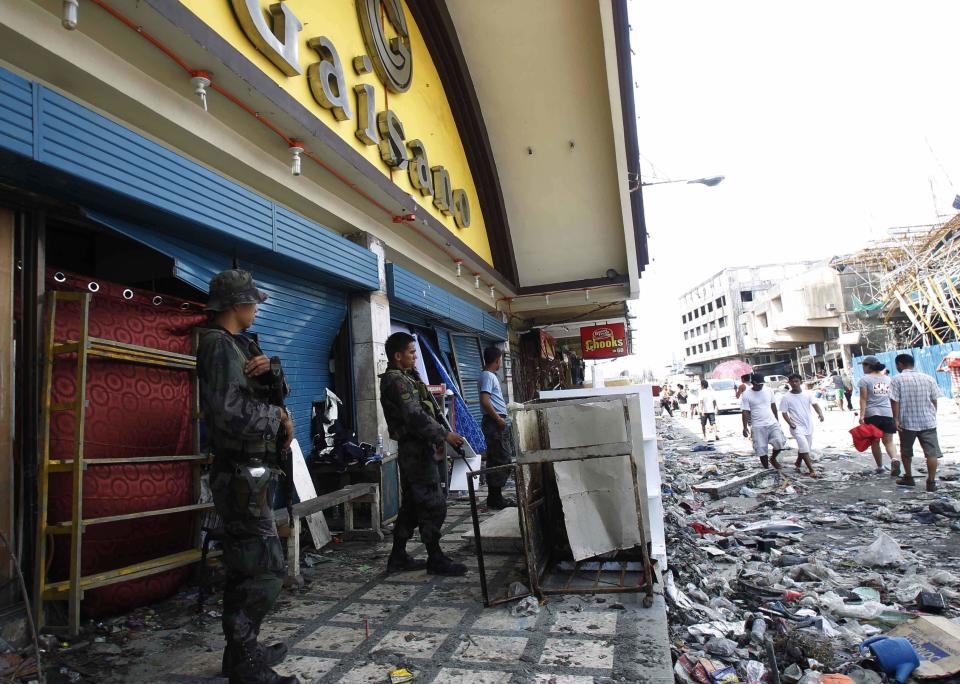 Police stand guard in front of a store to prevent people from taking items after super typhoon Haiyan hit Tacloban