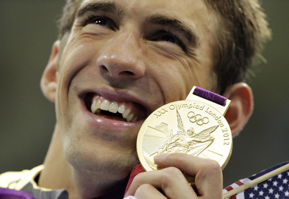 FILE - United States' Michael Phelps poses with his gold medal for the men's 4x200-meter freestyle relay swimming final at the Aquatics Centre in the Olympic Park during the 2012 Summer Olympics in London on July 31, 2012. (AP Photo/Matt Slocum, File)