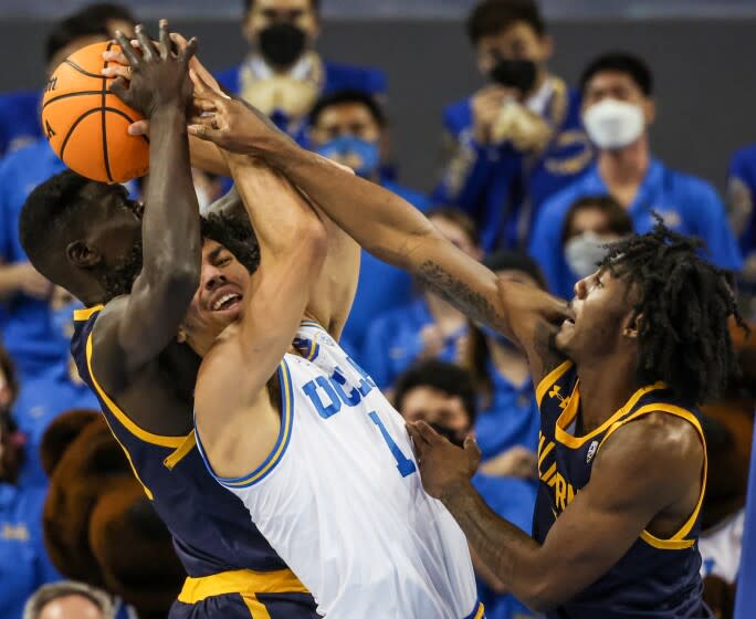 UCLA guard Jules Bernard struggles to control the ball as California's Kuany Kuany and Joel Brown fight for a rebound.