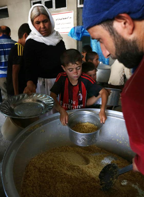 Iraqi Yazidi families who fled the violence in the northern Iraqi town of Sinjar, are given food at a school where they are taking shelter in the Kurdish city of Dohuk in Iraq's autonomous Kurdistan region, on August 5, 2014