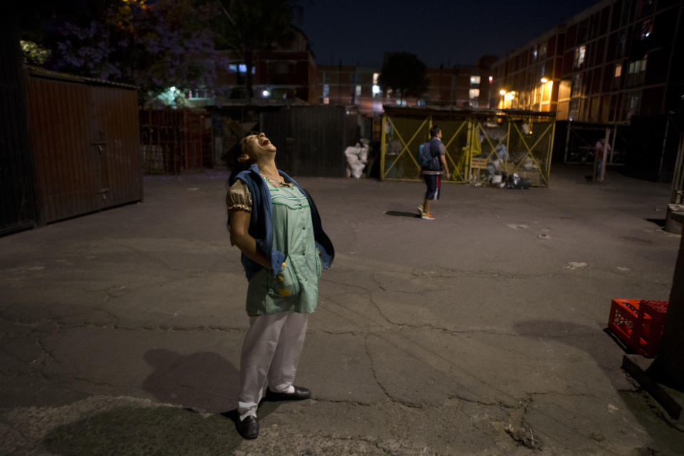 In this April 11, 2014 photo, Lourdes Ruiz laughs as she performs outside the Fortaleza housing complex where she lives in Mexico City's Tepito neighborhood. Ruiz is one of four local residents who teamed up with professional actors to write and perform fictionalized renditions of scenes from their own lives, dealing with themes such as child abandonment, violence, sexual abuse, hope, female strength and love. Ruiz, a vendor, is known as the queen of "albur," a word-play based on sexual double entendres. (AP Photo/Rebecca Blackwell)