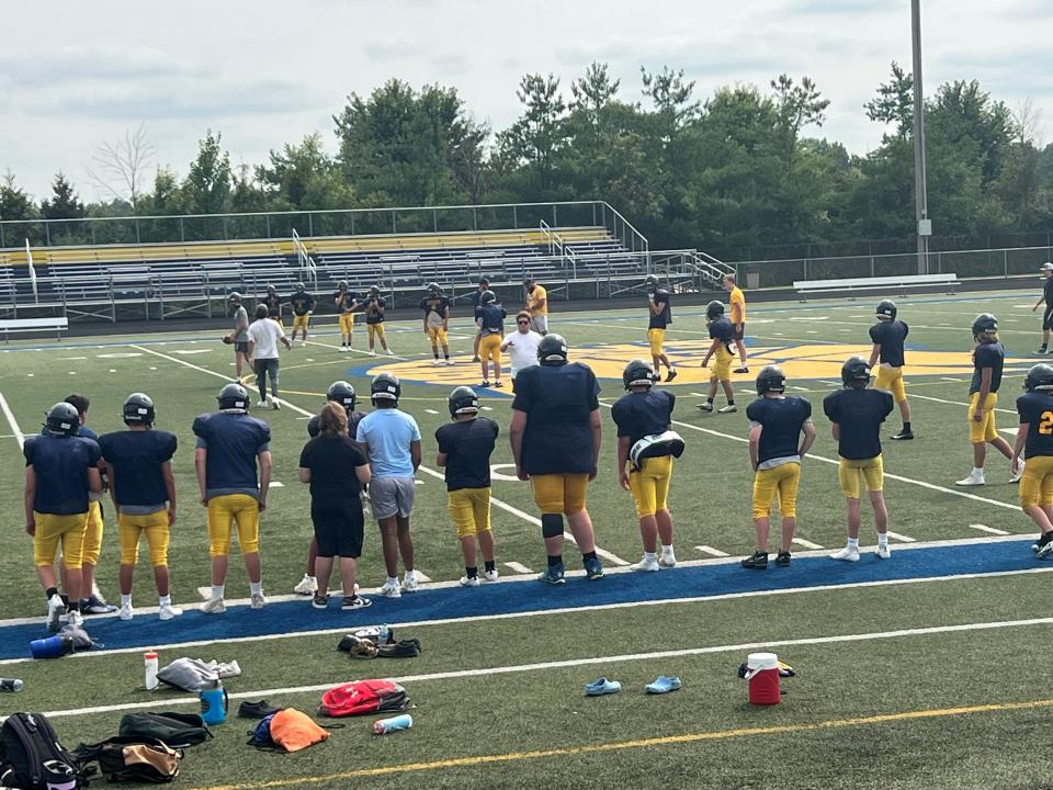 Eric Kilburn, Jr., a 6-foot-10 sophomore, with his teammates on the sideline at Goodrich JV football practice on Aug. 21, 2023. The 15-year-old has cleats that fit this season, thanks to Under Armour and the support of thousands of strangers that shared his story of size 22 shoes that were too small.
