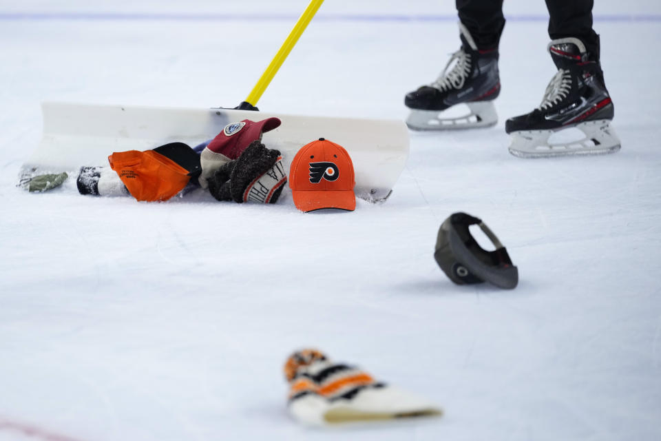 Workers clear hats from the ice after a third goal by Philadelphia Flyers' Travis Konecny during an NHL hockey game against the Washington Capitals, Wednesday, Jan. 11, 2023, in Philadelphia. (AP Photo/Matt Slocum)