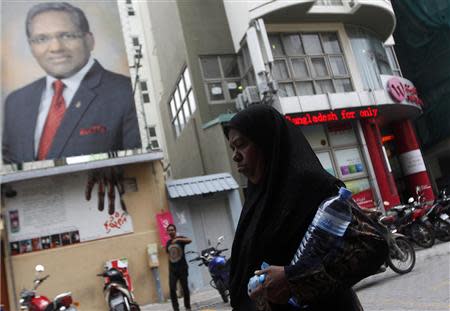 A woman walks past presidential election candidate Mohammed Waheed's election campaign poster in Male, September 5, 2013. Waheed will compete with Mohamed Nasheed, who was ousted as president in 2012. REUTERS/Dinuka Liyanawatte