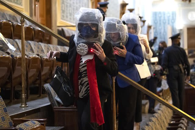 Tom Williams/CQ-Roll Call, Inc via Getty Images U.S. representatives are evacuated from the House chamber in gas masks as Donald Trump's supporters breach the Capitol on Jan. 6, 2021