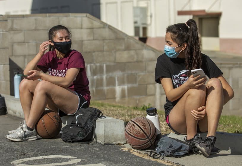 MONTEREY PARK, CA - MARCH 26, 2021: Kendall Tam, left, a senior at Mark Keppel High School and captain of the girls varsity basketball team, talks with Emily Liu, a junior, before start of a practice session at the school in Monterey Park. This was the first week back to practice since a year ago last March when everything came to a halt due to the coronavirus outbreak. (Mel Melcon / Los Angeles Times)