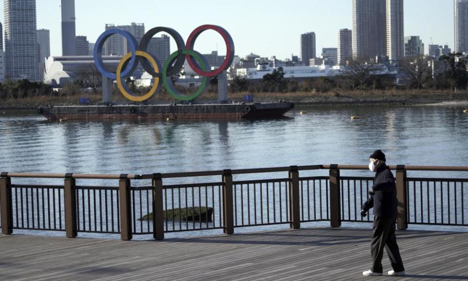 A man walks past the Tokyo 2020 Olympic rings wearing a mask