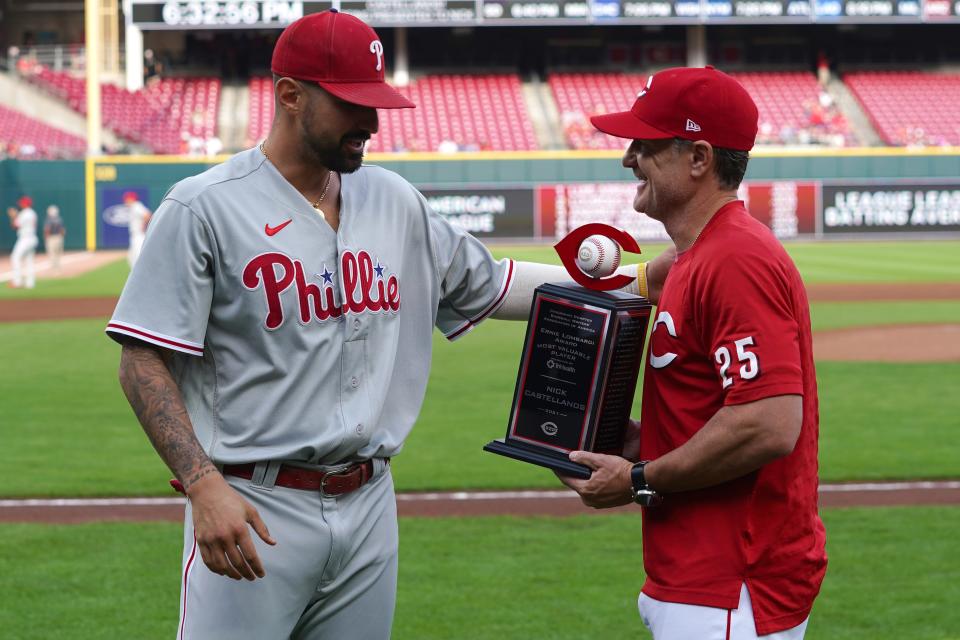 Philadelphia Phillies right fielder Nick Castellanos (8) is handed the Cincinnati Reds team most valuable player trophy by Cincinnati Reds manager David Bell (25) prior to the first inning of a baseball game, Monday, Aug. 15, 2022, at Great American Ball Park in Cincinnati. 