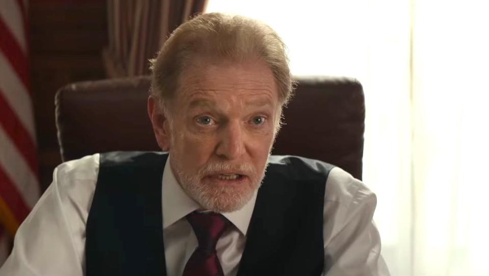 William Atherton as Walter Peck with a beard and black vest sits at a desk in Ghostbusters: Frozen Empire