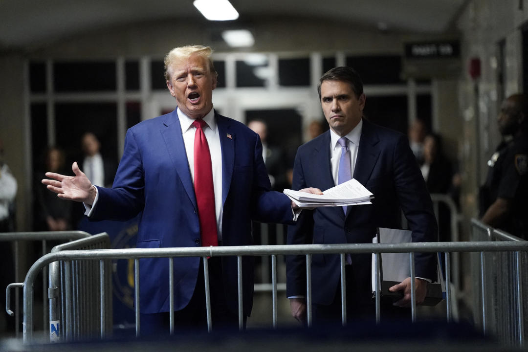 Donald Trump speaks to the press before leaving his hush money trial as defense attorney Todd Blanche looks on.