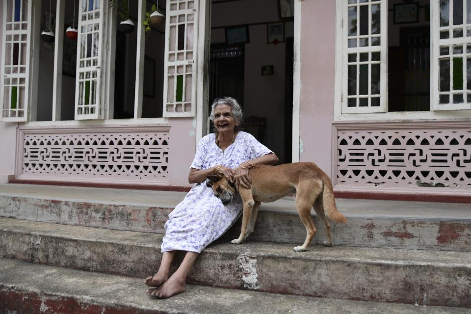 Baby Joseph Kalathungal, 99, pats her dog sitting outside her home in Chellanam, Kochi, Kerala state, India, March 24, 2023. While her family's 2.5 acres no longer produces viable yields, they still grow pokkali because they are part of a farmers' collective holding out against all-year fish farming. (AP Photo/R S Iyer)