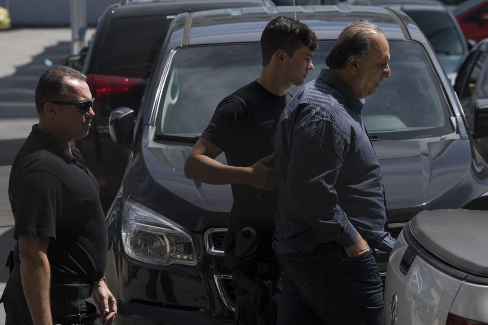 Rio de Janeiro Gov. Luiz Fernando Pezao, right, is escorted by police officers as they leave the Federal Police headquarters in Rio de Janeiro, Brazil, Thursday, Nov. 29, 2018. Pezao was arrested for allegedly taking about $10 million in bribes since 2007, adding to a string of corruption arrests of senior political figures. (AP Photo/Leo Correa)