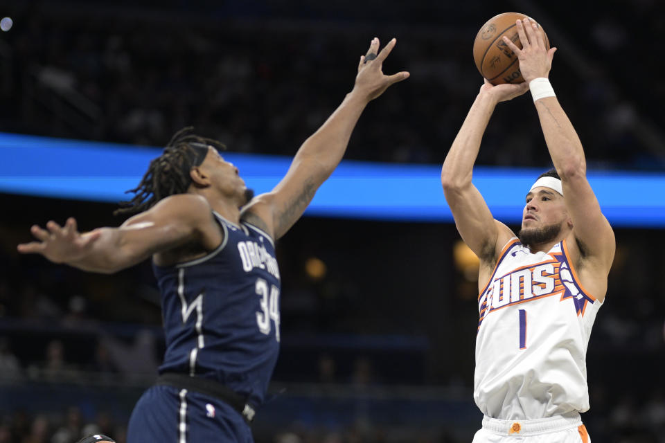 Phoenix Suns guard Devin Booker (1) shoots in front of Orlando Magic center Wendell Carter Jr. during the first half of an NBA basketball game, Sunday, Jan. 28, 2024, in Orlando, Fla. (AP Photo/Phelan M. Ebenhack)