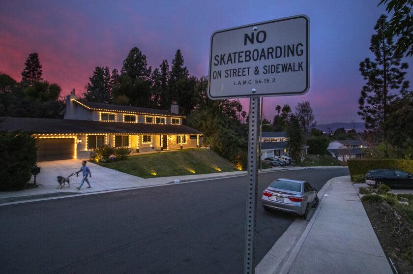 TARZANA, CA-JANUARY 6,2023:Arnab Pradhan walks his sister's dog Baxter, on Hermano Dr. in Tarzana, the only cul-de-sac in L.A. where there is an ordinance specifically making it illegal to skateboard. Pradhan said he is housesitting for his sister, who lives on the cul-de-sac. (Mel Melcon / Los Angeles Times)