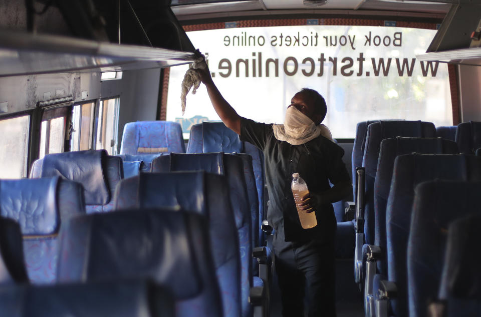 A Telangana State Road Transport Corporation (TSRTC) worker disinfects a bus as a precaution against COVID-19 in Hyderabad, India, Sunday, March 15, 2020. For most people, the new coronavirus causes only mild or moderate symptoms. For some, it can cause more severe illness, especially in older adults and people with existing health problems. (AP Photo/Mahesh Kumar A.)