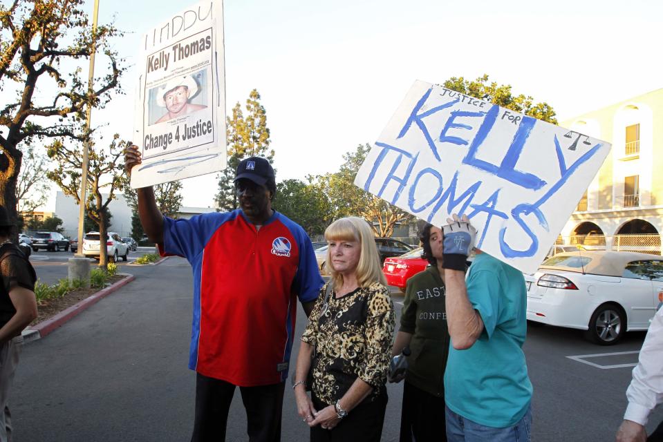 Cathy Thomas stands with supporters holding signs at a parking lot after speaking at a courthouse news conference on two former policemen being acquitted in the 2011 beating and stun-gun death of her son, in Santa Ana