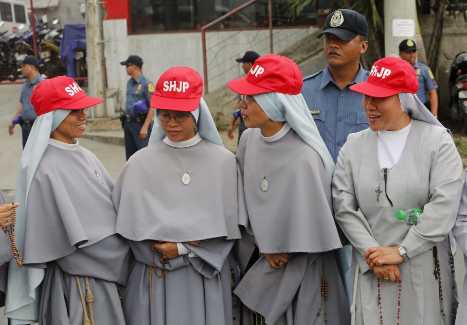 Catholic nuns from Sacred Heart Jesus Parish wait for the motorcade of Pope Francis to pass along a main street in Manila