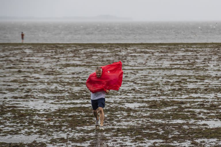 Dos personas caminan sobre el suelo expuesto de la bahía de Tampa debido a la marea baja y los intensos vientos generados por el huracán Ian, el miércoles 28 de septiembre de 2022, en Tampa, Florida. (Willie J. Allen Jr./Orlando Sentinel vía AP)