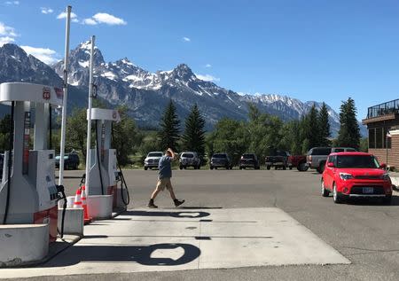 A man walks past gas pumps in front of Dornans Trading Post and Deli, with the Rocky Mountains Teton Range in the background in Moose, Wyoming, U.S. July 12, 2017. REUTERS/Ann Saphir