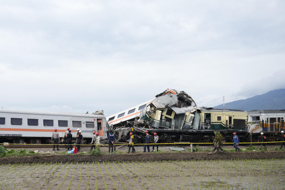 Inspectors work near the wreckage after the collision between two trains in Cicalengka, West Java, Indonesia, Friday, Jan. 5, 2024. The trains collided on Indonesia's main island of Java on Friday, causing several carriages to buckle and overturn and killing at least a few people, officials said. (AP Photo/Achmad Ibrahim)