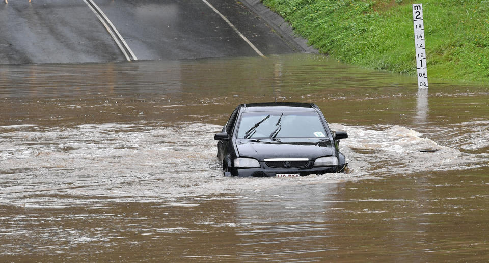 A car is seen caught in water during floods on Hardys Road at Mudgeeraba on the Gold Coast.