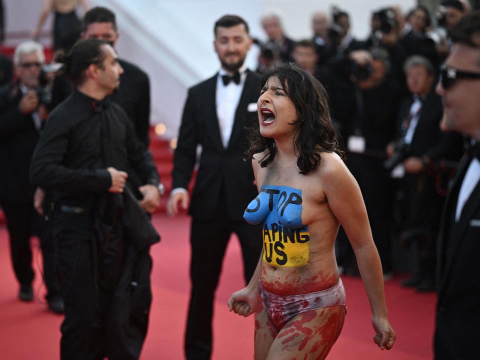 A woman with the Ukrainian national colours and "Stop raping us" painted on her body at the Cannes Film Festival on May 20, 2022.